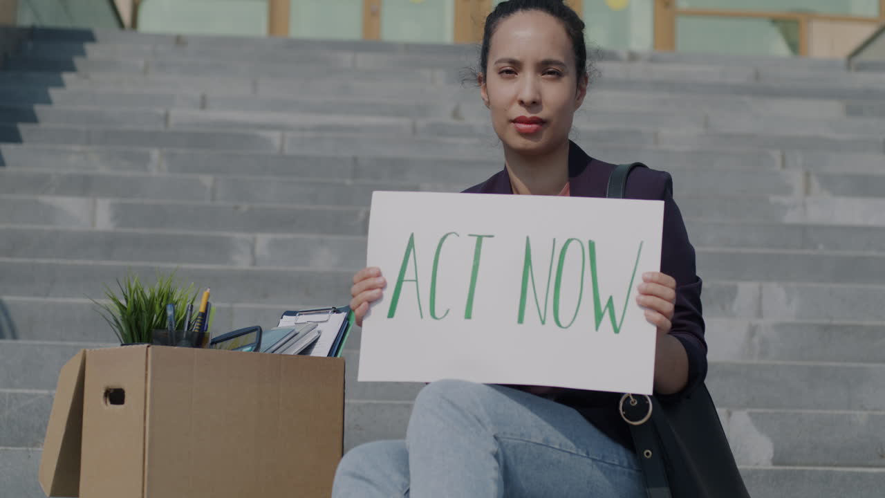 Woman on Stairs Holding Sign: "ACT NOW"