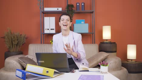 Home-office-worker-young-woman-waving-at-camera.