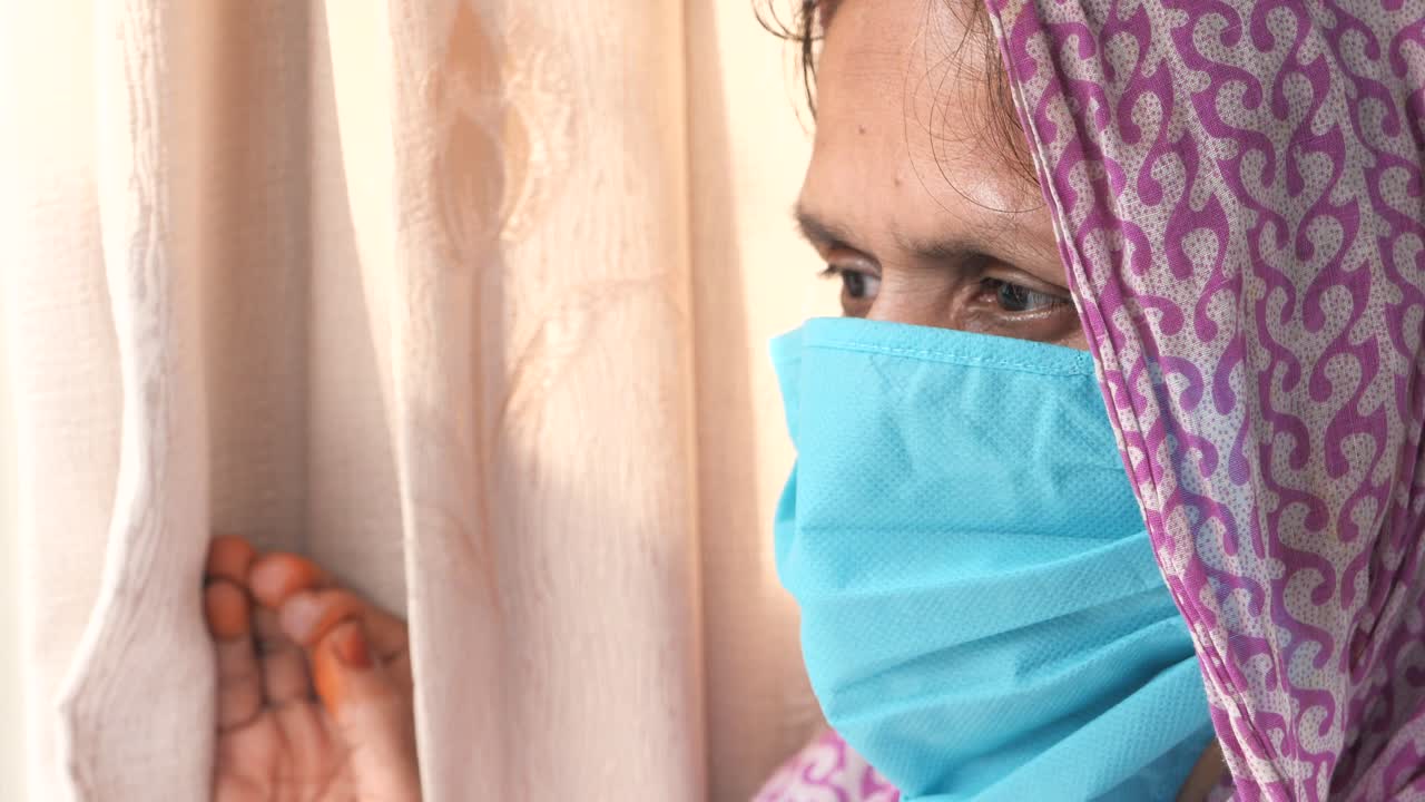 창문을 통해 보는 마스크를 입은 여자