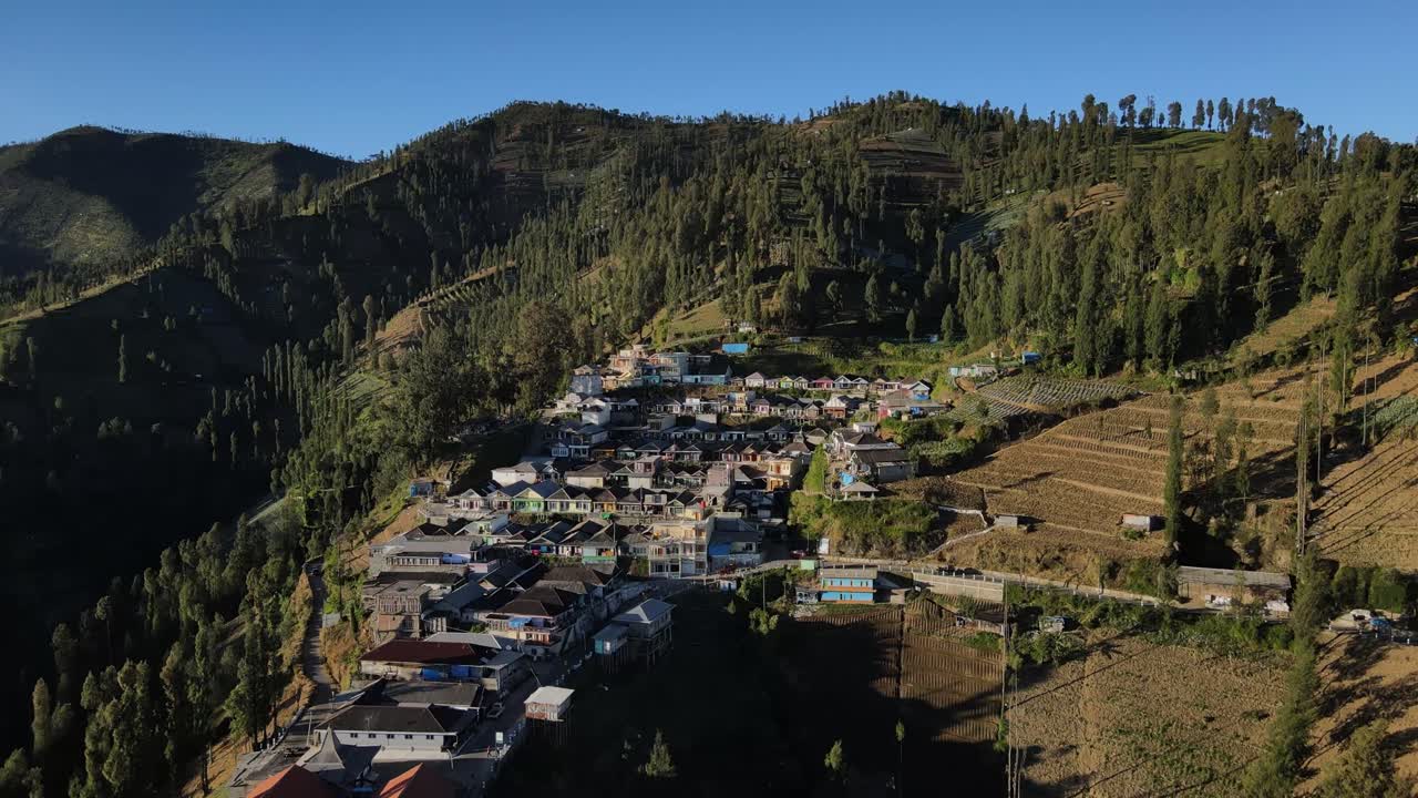 Countryside aerial footage of Indonesian highland village with agricultural land and dense tree lines