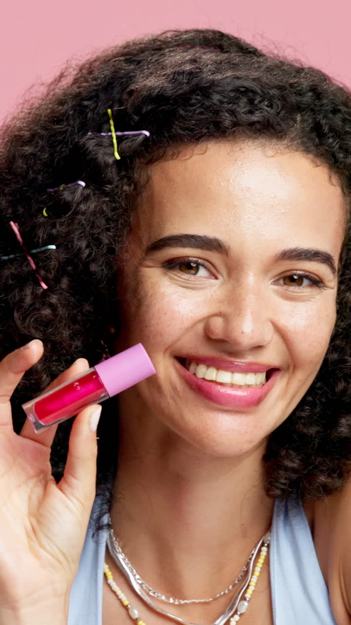 Woman with curly hair holding lip gloss