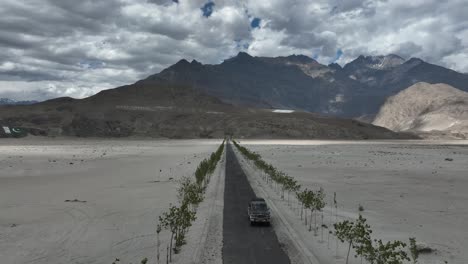imágenes de drones volando hacia atrás de un automóvil conduciendo por una hermosa carretera dentro de una montaña en la zona norte de pakistán
