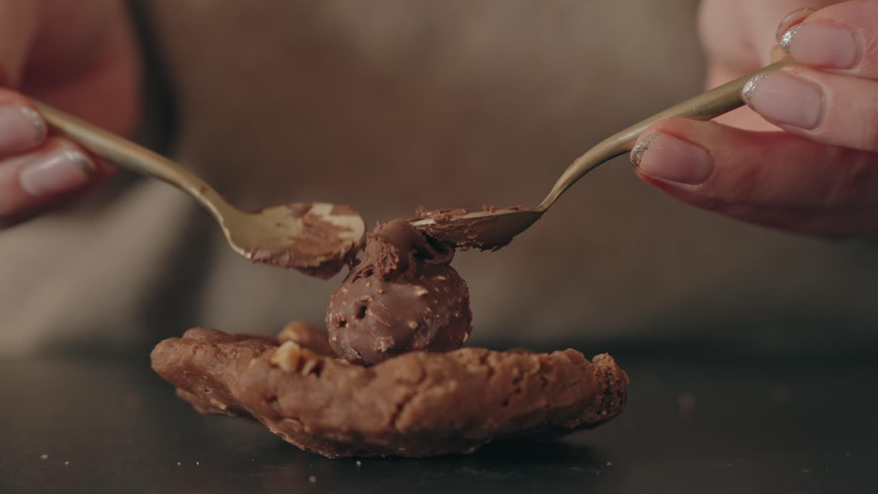 Hands shape chocolate cookie dough with two spoons in close up