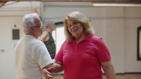 medium shot of pretty senior couple dancing together in ballroom