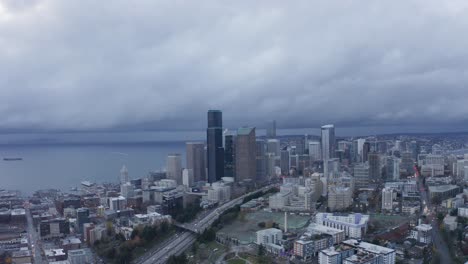 drone slowly moving towards seattle's downtown skyscrapers with interstate 5 underneath on an overcast and gloomy day