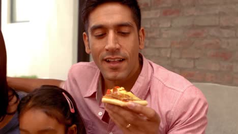 smiling hispanic family eating pizza in living room