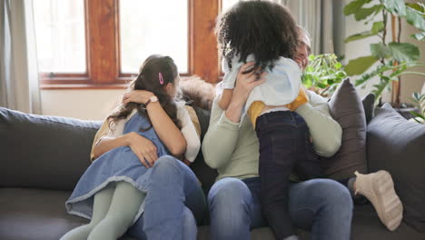 family, parents and children hug on sofa