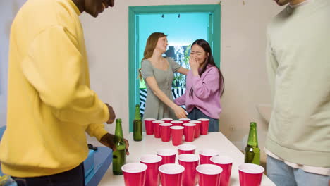 jóvenes amigos multiétnicos jugando pong de cerveza en casa