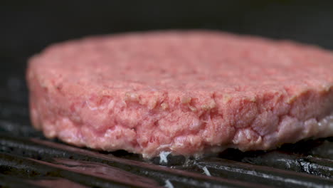 close up, raw hamburger cooking over a flaming backyard barbecue grill