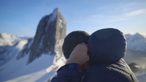 Un-Hombre-Se-Pone-Un-Sombrero-De-Nieve-Con-El-Icónico-Monte-Segla-De-Noruega-Al-Fondo