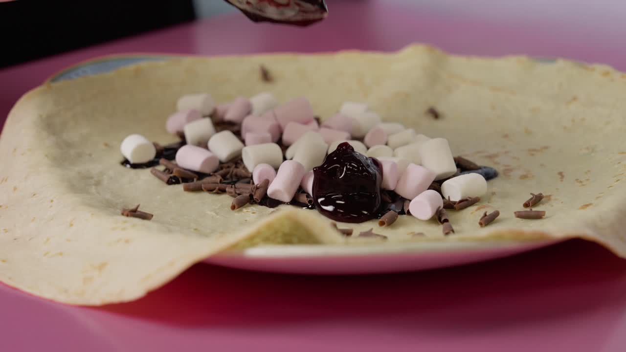 esparciendo mermelada de cereza sobre un crepe con chocolate