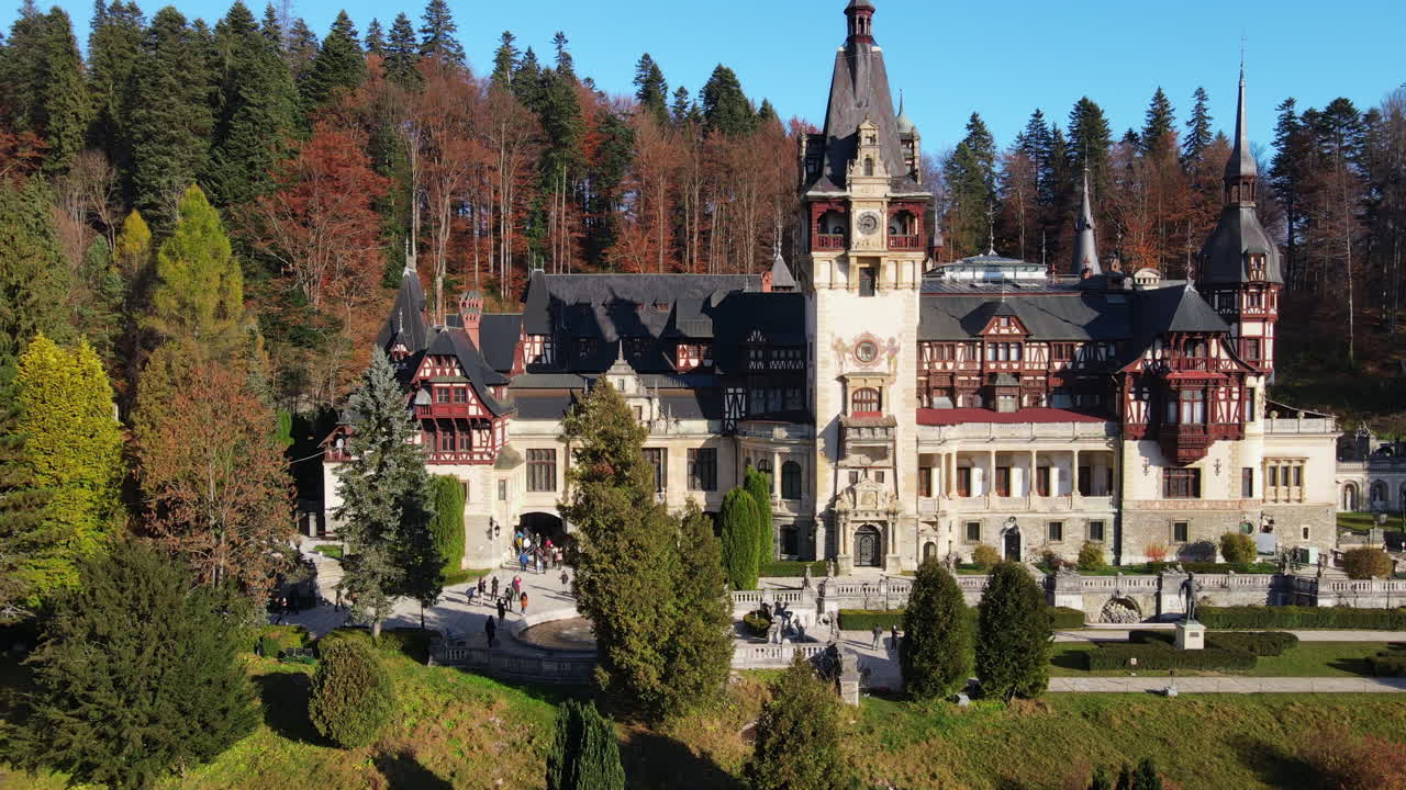 Aerial drone view of The Peles Castle in Romania. Castle with gardens in Carpathians, forest around it, tourists