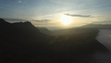 Drone-shot-of-Bromo-surrounding-mountains-and-village-in-the-mist-of-the-morning