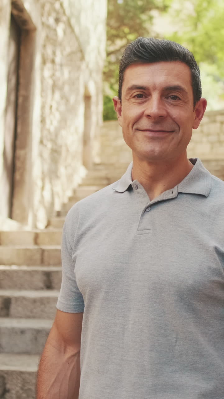 Hombre sonriente cruza los brazos en escalones de piedra