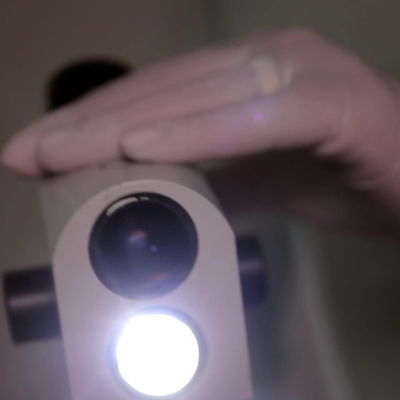 Close-up of a microscope with a gloved hand