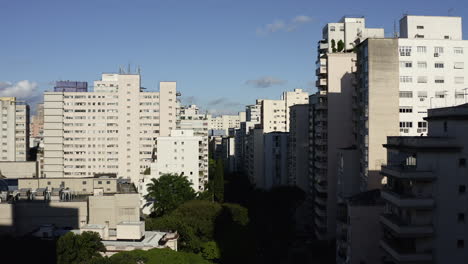 toma aérea de drones del paisaje urbano de una gran metrópolis que pasa a través de grandes edificios en la ciudad de sao paulo, brasil, dolly in y crane up camera subiendo revelando la ciudad en el distrito de higienopolis