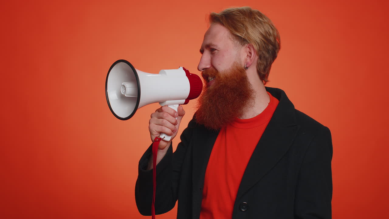 hombre barbudo sonriente hablando con megáfono, proclamando noticias, anunciando en voz alta anuncios de venta