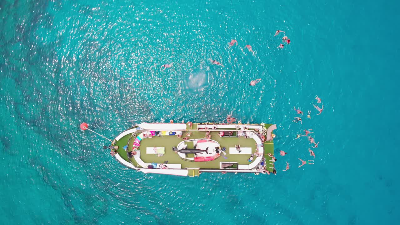 Aerial vertical drone shot of a cruise ship with people swimming around. Blue Lagoon, Ayia Napa, Cyprus