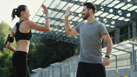 young jogger couple running in the stadium, then they stop and look at camera