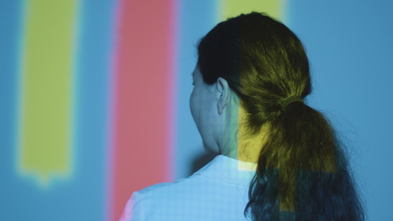 mujer visitando una exposición de arte inmersiva con proyección de formas y patrones en la pared 5