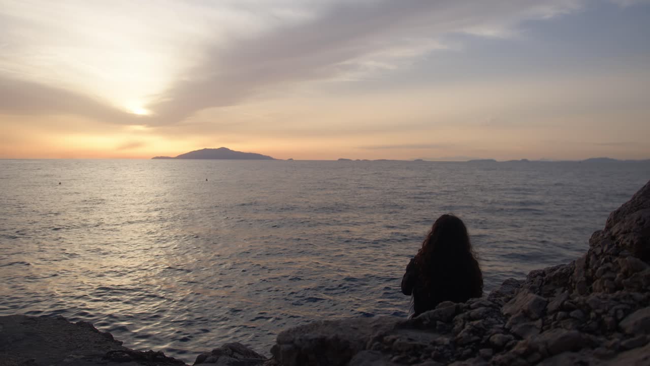 Girl Silhouetted Against Sunset Over Ocean