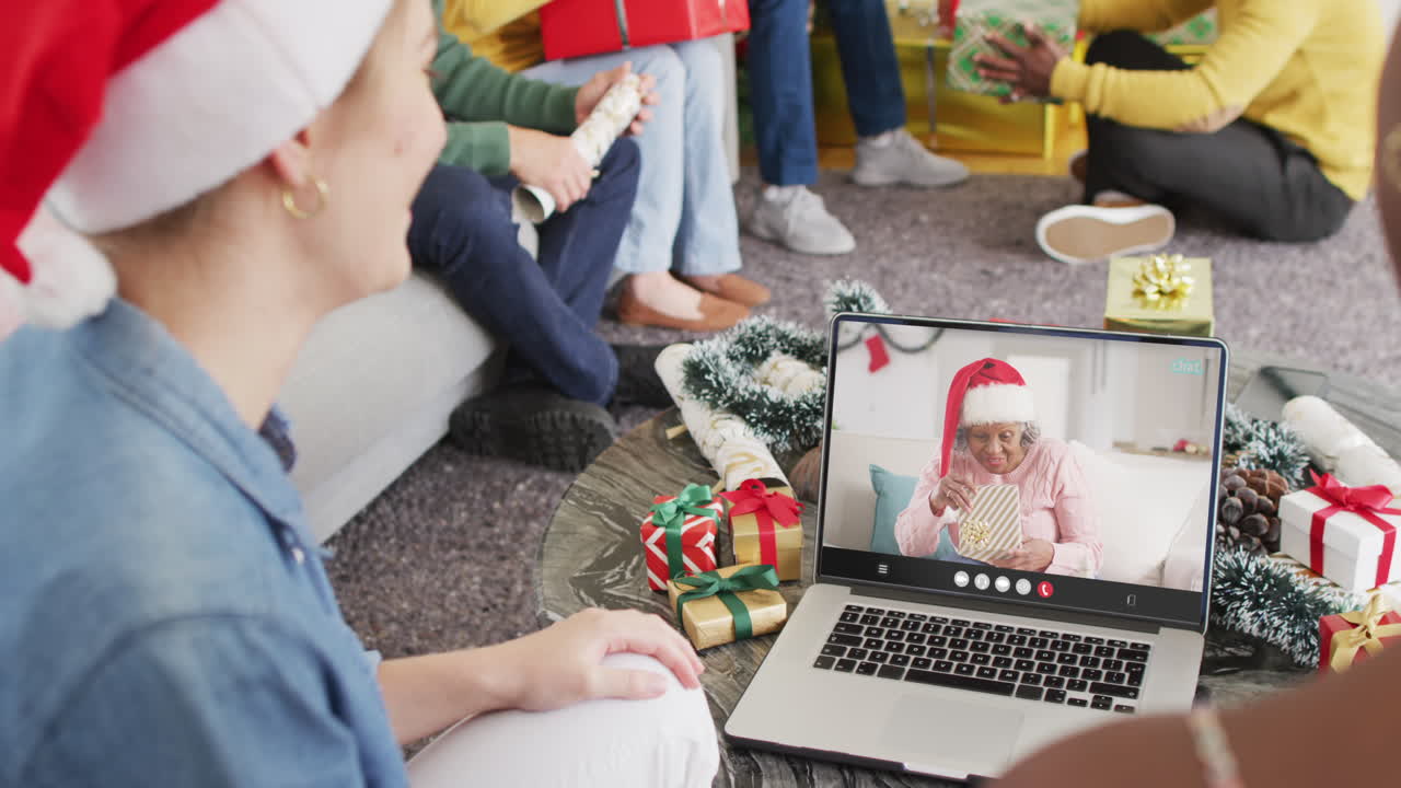 un grupo diverso de amigos teniendo una videoconferencia de navidad con una anciana afroamericana