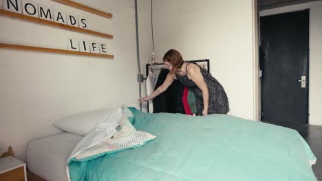 a young woman makes her bed neatly