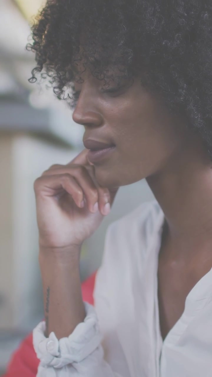 Vertical video: Woman shifting from chin-resting to tapping phone screen, starting home tech task