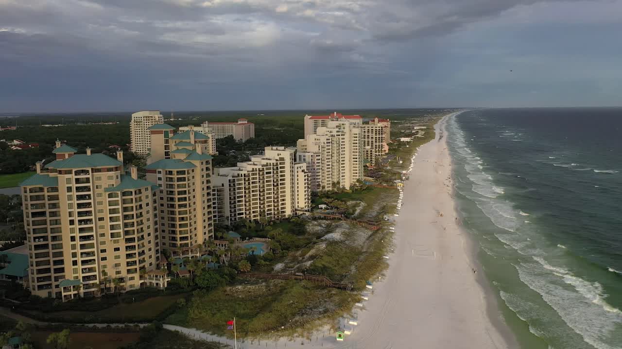 Volando lungo la spiaggia di sabbia bianca di San Destin, FL, durante l'ora d'oro con alcune nuvole scure nel cielo