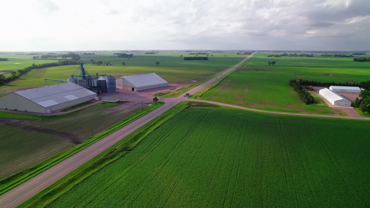 Aerial view of a red tanker semi-truck driving by agricultural silos in rural Minnesota farmland.