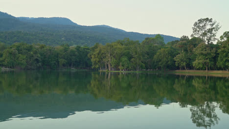 lago ang kaew en la universidad de chiang mai con montaña boscosa y cielo crepuscular