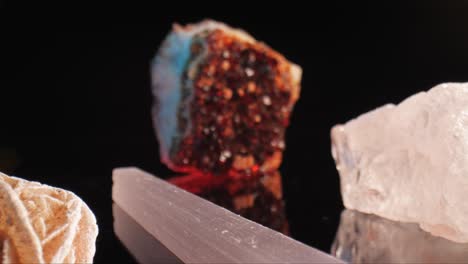 glimmering gems sparkle as dolly gracefully moves in, featuring desert rose, selenite, citrine and quartz under studio lighting on a black background