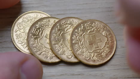 male hand stacked golden shiny swiss coins on wooden table,close up