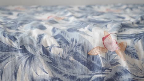un primer plano de una sábana de cama con patrones de hojas tropicales