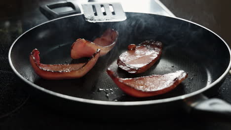 rebanadas fritas de tocino casero en una sartén caliente