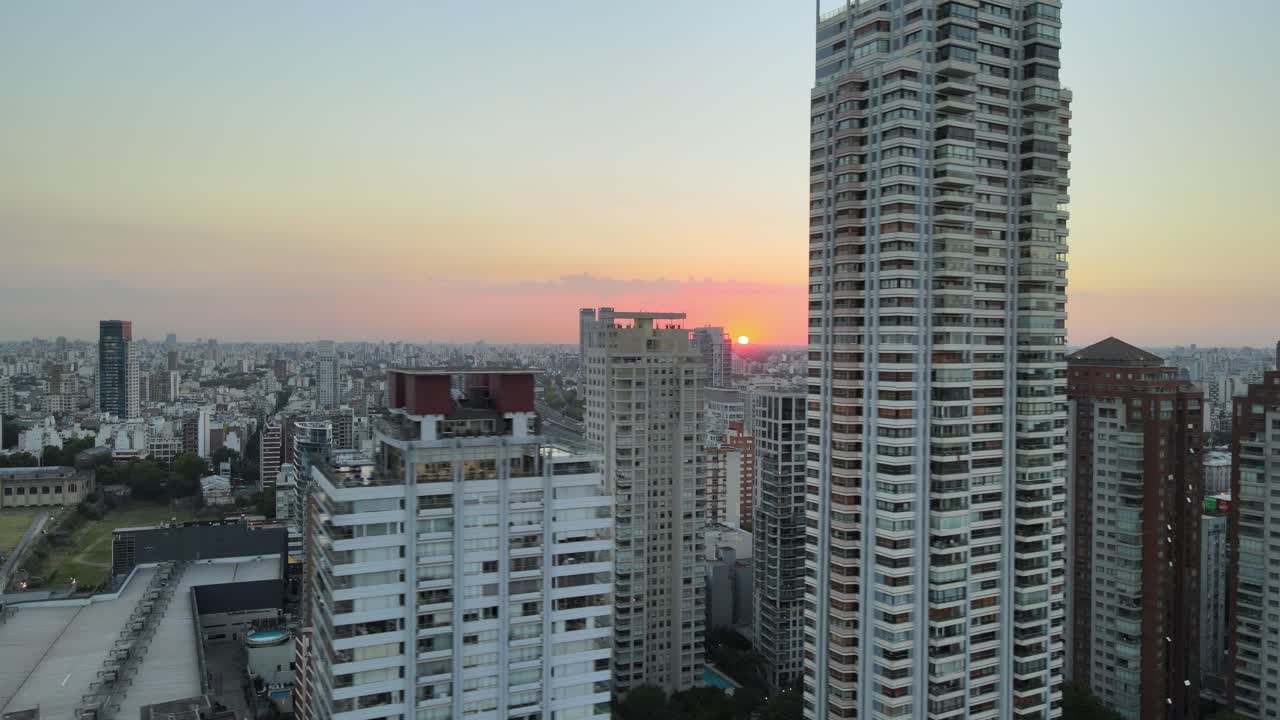 toma de órbita aérea de la puesta de sol en el horizonte y las torres del horizonte de la ciudad en primer plano