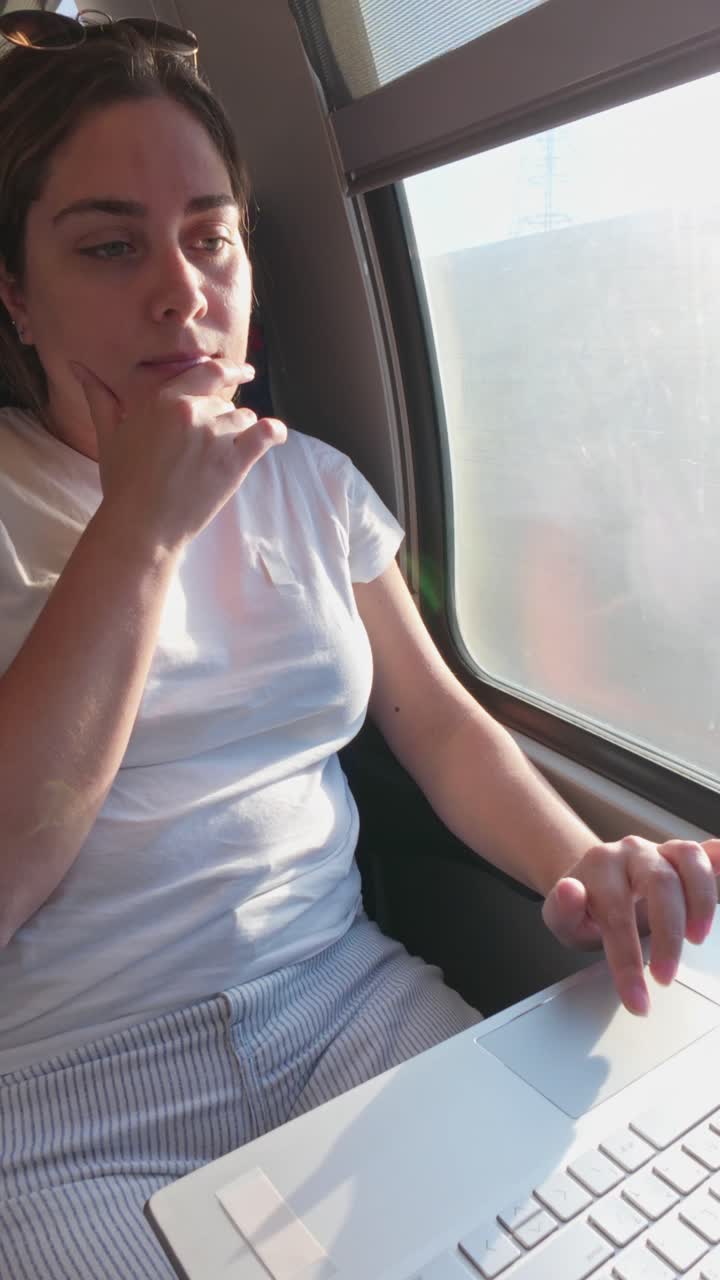 Young Woman Scrolling on a Laptop Trackpad While Commuting
