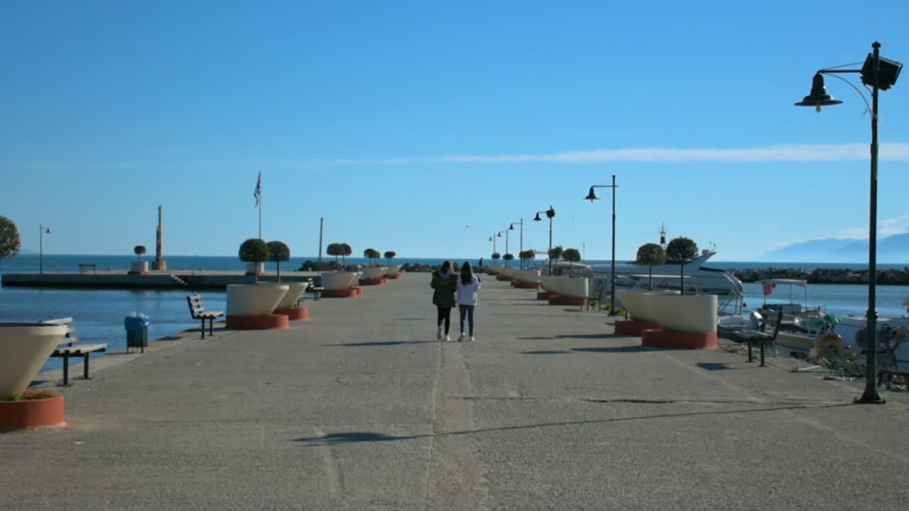 그리스 아테네 근처의 작은 도시에서 항구를 걷고 있는 두 소녀