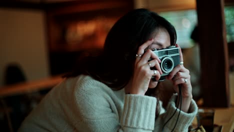 woman taking photo with vintage camera in cafe