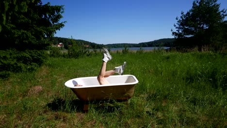 there is a bathtub by the lake and a girl in it.