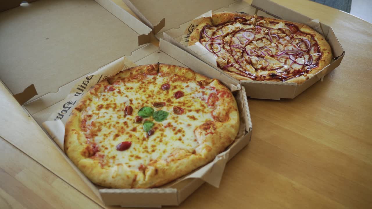 the handheld shot of man's hand opening delivered Italian pizza in a cardboard box on the table at home, closeup
