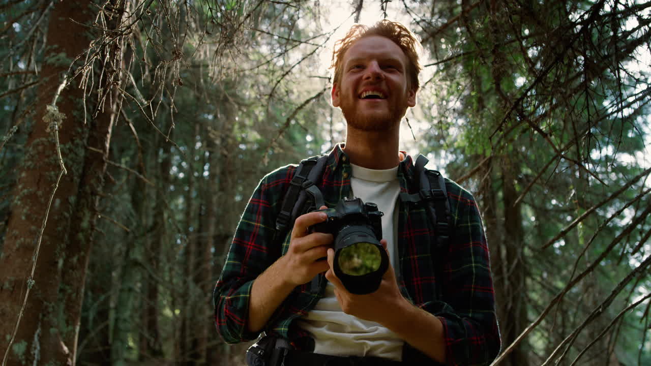 fotógrafo mirando fotos en la cámara. hombre con cámara disparando en el bosque