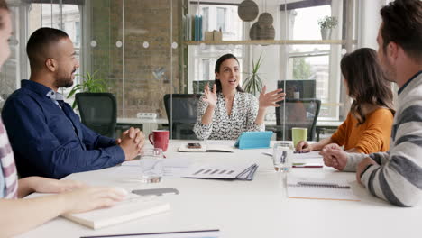 diverse business people clapping in creative team meeting celebrating success in casual modern office boardroom with natural light and large open windows