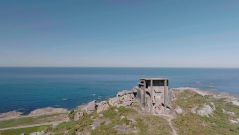 aerial drone forward moving shot of an old abandoned watchtower used in the spanish civil war overlooking the beautiful coastline at daytime