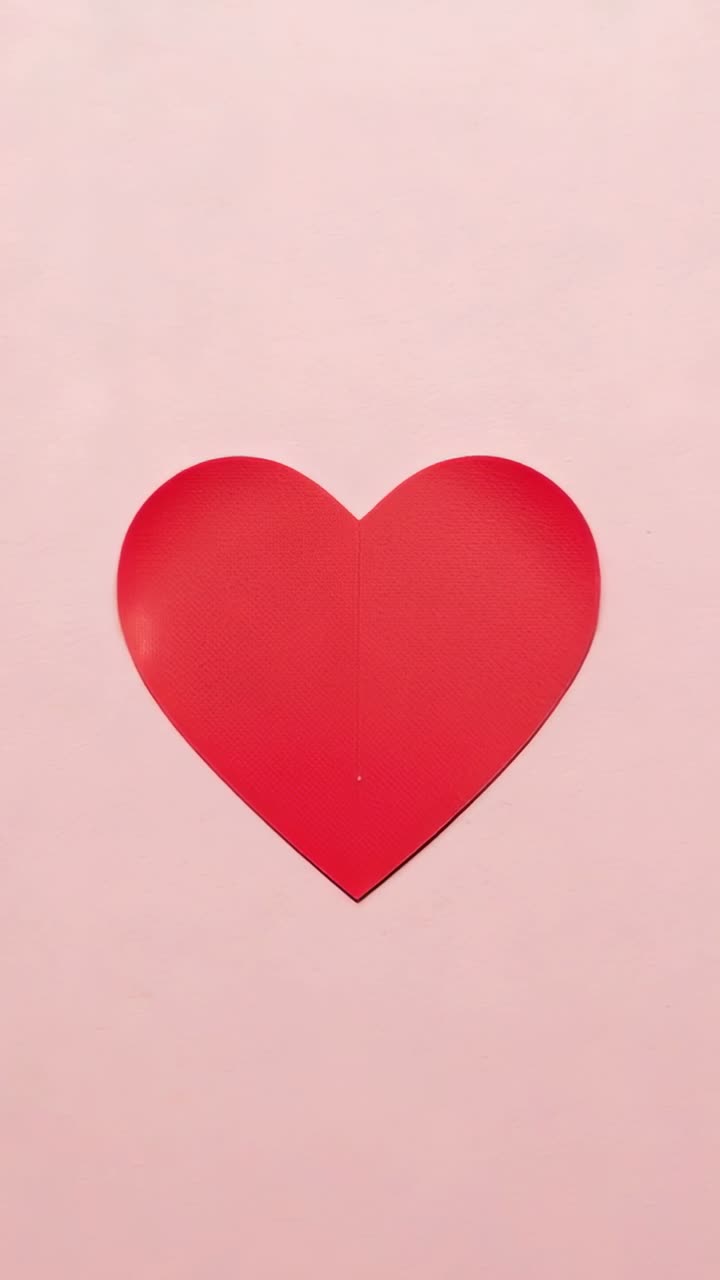Video verticale: cuore di carta rosso pulsante che reagisce alle inquadrature su sfondo rosa con pieghe e pois
