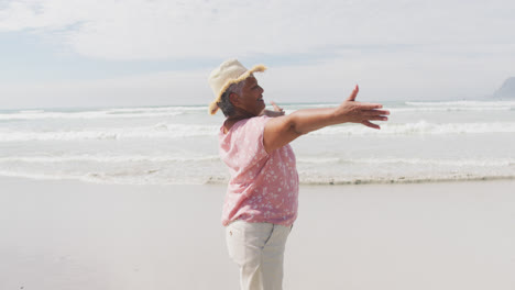 mixed race senior woman spinning with open hands at the beach