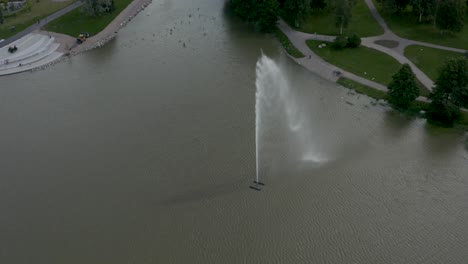 still aerial shot of a large fountain with birds flying around near a park in finland