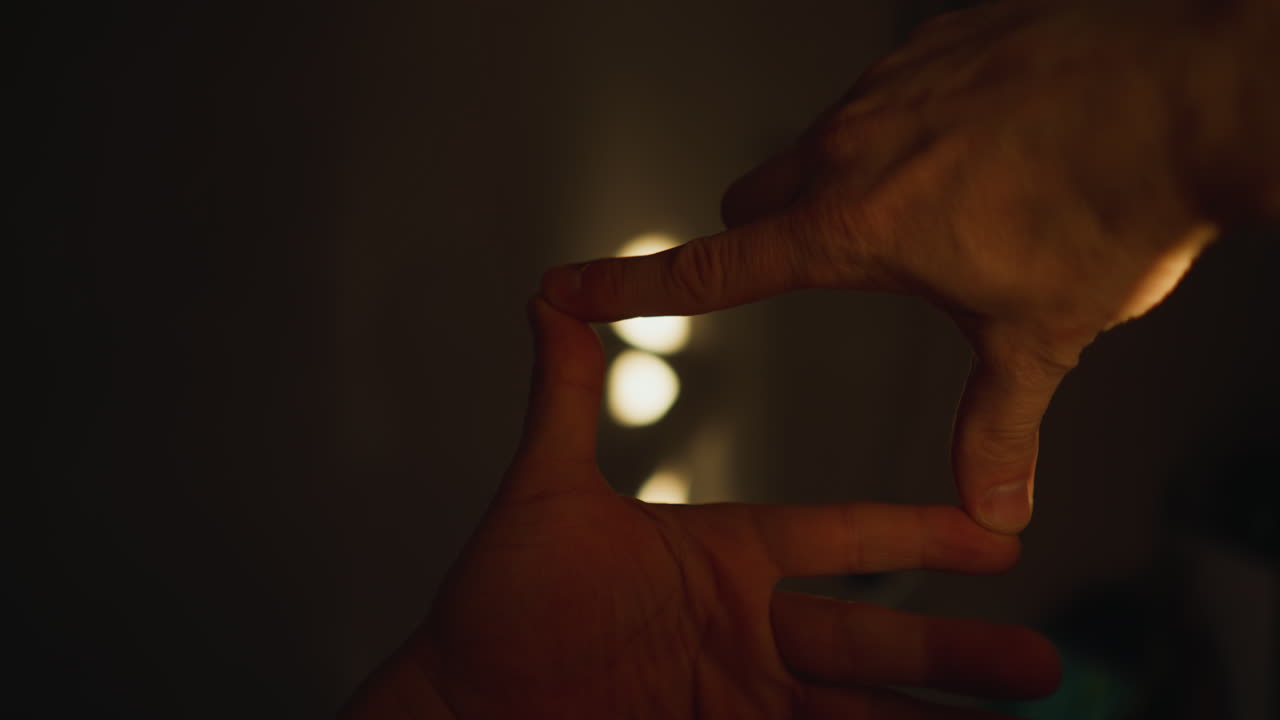 POV of hands forming a cinematic frame, capturing shadows on the wall through sunlight, shot with a hand-held camera