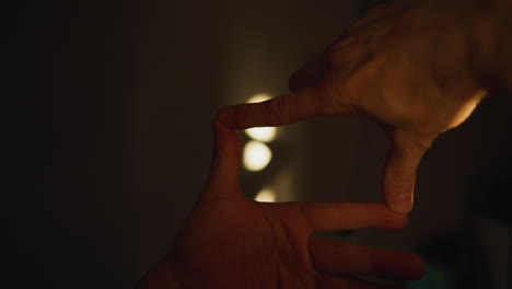 손이 영화 프레임을 형성하고, 빛을 통해 벽에 그림자를 포착하고, 손에 들고 있는 카메라로 촬영합니다.