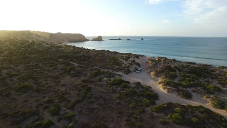 Beautiful-aerial-shot-of-a-couple-camping-on-a-beautiful-secluded-clifftop